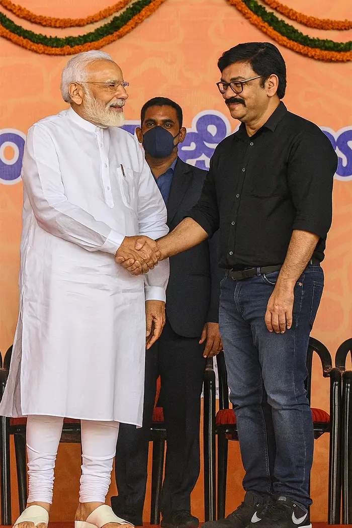 Narendra Modi warmly shakes hands with a confident man on a grand decorated stage